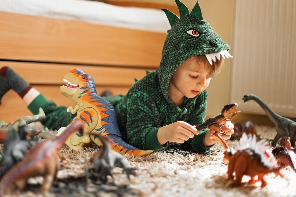 Young boy playing with toy dinosaurs during imaginative play, illustrating how understanding you child's play can give us clues about their emotions and inner world.